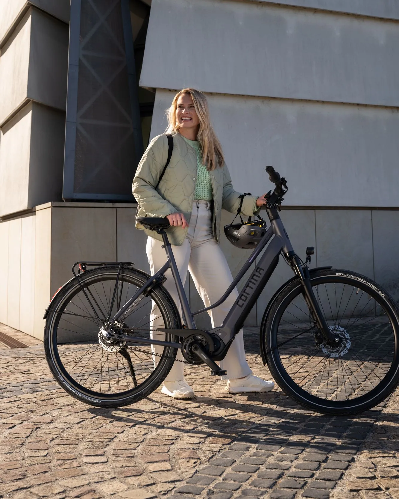 woman standing next to a cortina e-mozzo electric women's bike